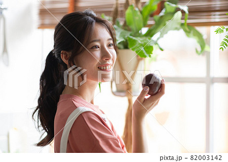 キッチンでフルーツをもつ可愛い女性 82003142