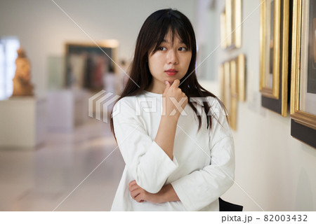 Thoughtful chinese woman standing in art museum near the painting Thoughtful chinese woman standing in art museum near the painting 82003432