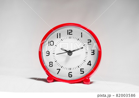 Small red alarm clock show the running time. A modern clock with red frame. Smile face of a clock. Close up on a red plastic watch with second pointer on white background. Ten after twelve . 82003586