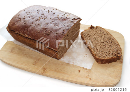 Sliced dark rye hemp seed bread on paper and wooden board isolated on white background Sliced dark rye hemp seed bread on paper and wooden board isolated on white background 82005216