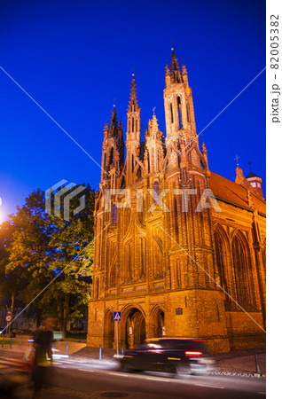Illuminated beautiful old Orthodox Church in the old Town of Vilnius. Building with Gothic towers on The Main city street at night after sunset with the light trails. Car's motion blur 82005382