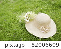 芝生の上に置いた麦わら帽子と花束 82006609