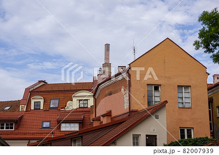 Abstract conceptual architecture of vintage roofs of houses with windows, balconies and oven and ventilation pipes against blue sky with clouds in old Town. Apartments in the attic against skyline 82007939