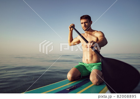 Young fit man on paddle board floating on lake. Young fit man on paddle board floating on lake. 82008895