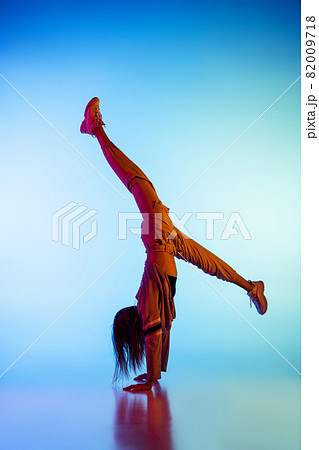 Young sportive girl dancing break dance alone isolated on colorful background at dance hall in neon light. Youth culture, movement, style and fashion, action. Young sportive girl dancing break dance alone isolated on colorful background at dance hall in neon light. Youth culture, movement, style and fashion, action. 82009718