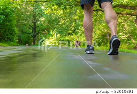 Legs in sneakers close up athlete runs in the park outdoors, around the forest, oak trees green grass young enduring athletic athlete healthy runner nature, workout jogger young legs jog, woods 82010891
