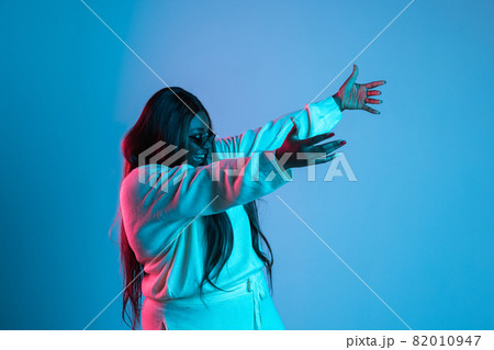 One African beautiful woman with long straight hair isolated on blue studio background in neon light. Concept of human emotions One African beautiful woman with long straight hair isolated on blue studio background in neon light. Concept of human emotions 82010947