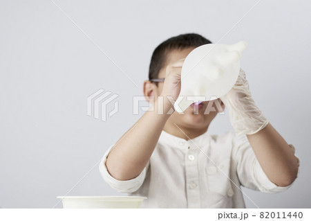 A little kid blowing medical gloves as balloon against the white background A little kid blowing medical gloves as balloon against the white background 82011440