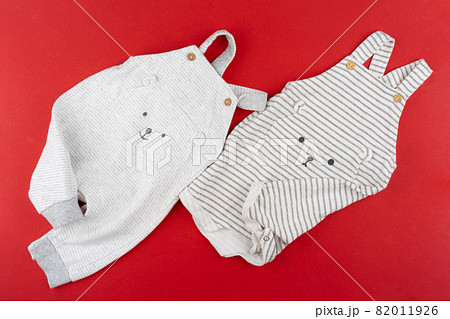 Baby clothes top view on red background Baby clothes top view on red background 82011926
