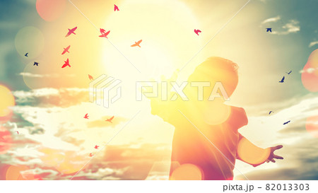 Freedom feel good and travel adventure concept. Copy space of silhouette man rising hands on sunset sky double exposure colorful bokeh and bird fly background. 82013303