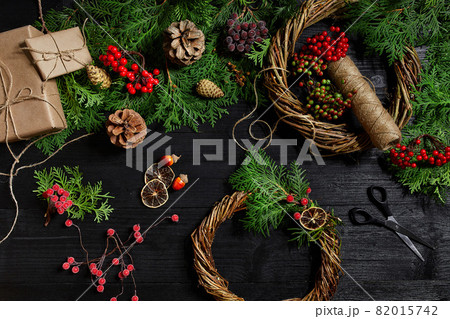 Make a Christmas wreath with your own hands. Spruce branch, Christmas wreath and gifts on a black wooden background Make a Christmas wreath with your own hands. Spruce branch, Christmas wreath and gifts on a black wooden background 82015742