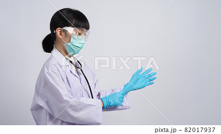 Wearing gloves. Asian doctor wear blue rubber nitrile hands glove. Doc with a mask putting on gloves. isolated white background copy space. Health care protection coronovirus pandemic concept. 82017937