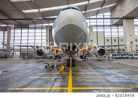 Frontal view to an white and grey colored airplane in maintenance hall 82018456