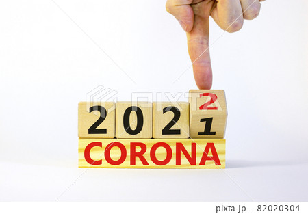 Symbol of covid-19 pandemic in 2022. Doctor turns a wooden cube and changes words 'corona 2021' to 'corona 2022'. Beautiful white background, copy space. Medical, covid-19 pandemic in 2022 concept. 82020304