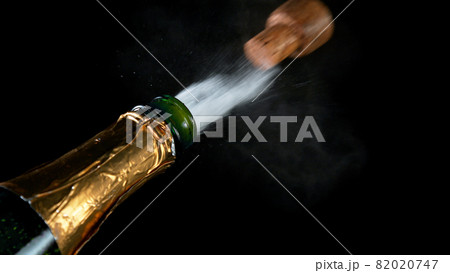 Freeze motion of Champagne explosion with flying cork closure, opening champagne bottle closeup 82020747