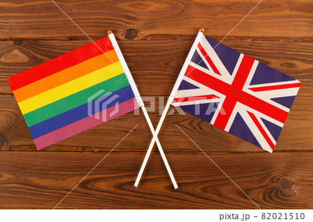 Rainbow flag LGBT and flag of Great Britain on brown wood planks background. LGBT Pride Month. LGBTQ. LGBTQIA. Close Up. Top view Rainbow flag LGBT and flag of Great Britain on brown wood planks background. LGBT Pride Month. LGBTQ. LGBTQIA. Close Up. Top view 82021510
