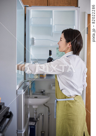 冷蔵庫から食材を取り出すエプロン姿の若い女性 82022286
