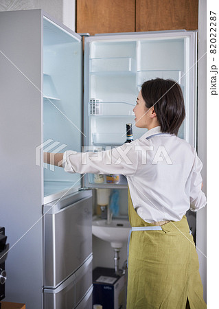 冷蔵庫から食材を取り出すエプロン姿の若い女性 冷蔵庫から食材を取り出すエプロン姿の若い女性 82022287