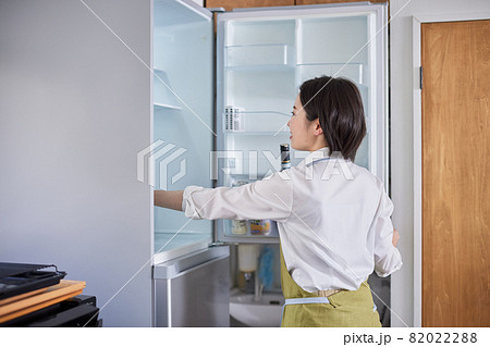 冷蔵庫から食材を取り出すエプロン姿の若い女性 82022288
