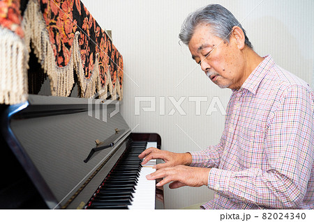 趣味でピアノを弾くシニア男性 82024340