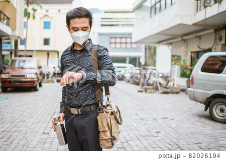Businessman walking trough sidewalk smiling looking at his wrist watch 82026194