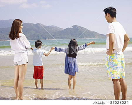 asian family with two children having fun on beach 82028024