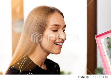 Surprised young woman opens a pink box with a present . 82028430