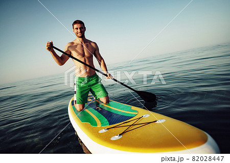 Young fit man on paddle board floating on lake. Young fit man on paddle board floating on lake. 82028447