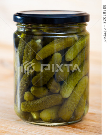 Pickled cucumbers with spices in glass jar on a wooden surface Pickled cucumbers with spices in glass jar on a wooden surface 82029589
