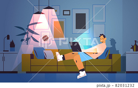 schoolboy looking at laptop screen teenager lying on sofa in dark night home room 82031232