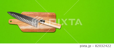 Traditional Japanese gyuto chief knife on a cutting board. green banner background 82032422