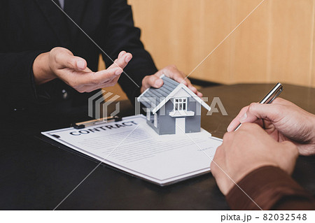 A real estate agent with a house model is talking to clients about buying home insurance and having customers sign contracts under the formal contract agreement. Home rental and insurance concept A real estate agent with a house model is talking to clients about buying home insurance and having customers sign contracts under the formal contract agreement. Home rental and insurance concept 82032548