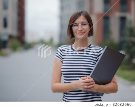woman walking with laptop in city street woman walking with laptop in city street 82032666
