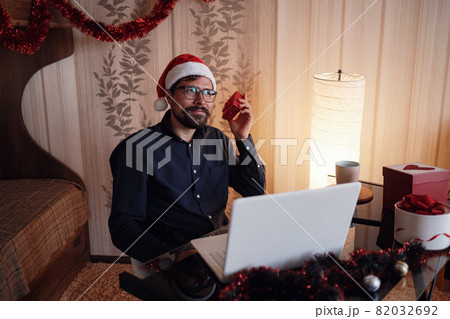 Virtual Christmas day house party. Man smiling wearing Santa hat 82032692