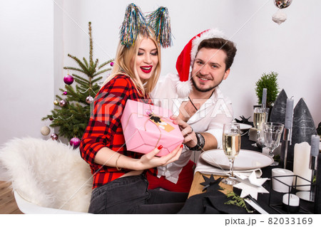 Picture showing group of friends celebrating Christmas at home and giving presents to each other 82033169