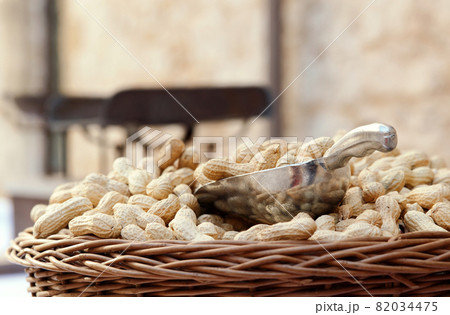 Wicker basket of raw organic peanuts in shell with metal scoop at outdoor market, copy space 82034475