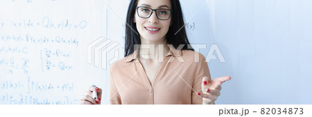 Portrait of woman teacher with glasses near school board 82034873