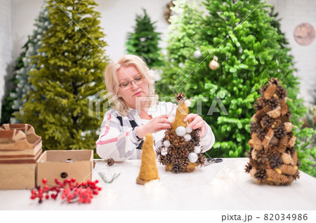 Elderly caucasian woman making cones decoration for christmas. 82034986