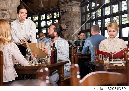 Guests of the country restaurant discuss menu with waitress 82036380
