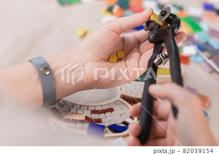 Hands of master working on new modern colorful mosaic. Close-up 82039154