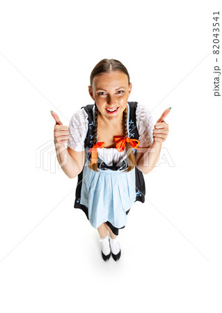 High angle view of sexy Oktoberfest woman, waitress wearing a traditional Bavarian or german dirndl isolated on white studio background. High angle view of sexy Oktoberfest woman, waitress wearing a traditional Bavarian or german dirndl isolated on white studio background. 82043541