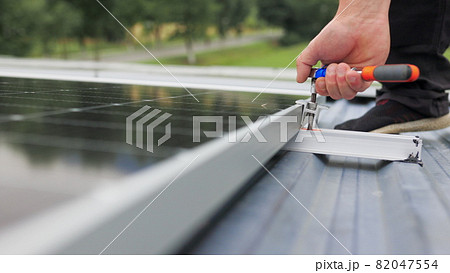 Mounting solar panel, installing solar panels on the roof of the house. Connection of solar panels. Close up of worker installing and working on maintenance of photovoltaic panel system installed. 82047554