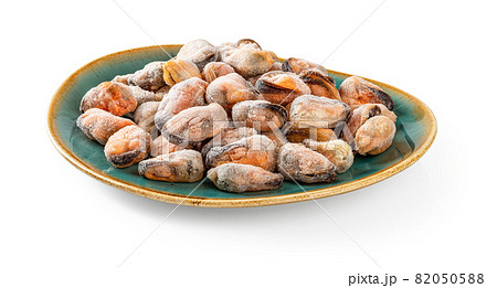 Frozen peeled mussels on an oval turquoise ceramic plate isolated on a white background. Frozen peeled mussels on an oval turquoise ceramic plate isolated on a white background. 82050588
