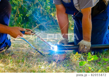 Hands of workers welding metal pipes with electric arc welding. Hands of workers welding metal pipes with electric arc welding. 82055872