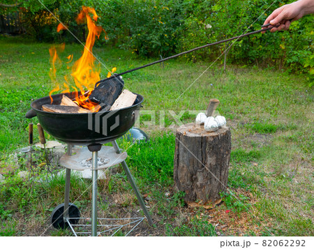 Freshly lit barbecue fire with logs of burning wood over small chips of kindling in a portable BBQ Freshly lit barbecue fire with logs of burning wood over small chips of kindling in a portable BBQ 82062292