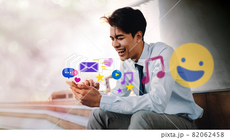 Smiling Young Asian Businessman Using Mobile Phone in the City. Enjoying Social Media application. surrounded by many icons 82062458