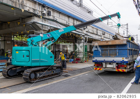線路脇の道路で荷物をトラックに積むクレーン車 82062935