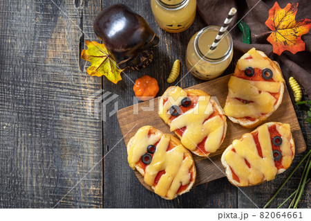 Halloween party food. Halloween mummies mini pizzas on a wooden table. Top view flat lay background. Copy space. Halloween party food. Halloween mummies mini pizzas on a wooden table. Top view flat lay background. Copy space. 82064661