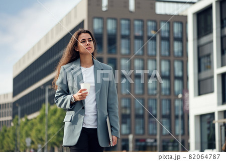 Young beautiful business woman at casual clothes near office centre with cup of coffee. Lunch break among working day. Business lifestyle and success concept. 82064787