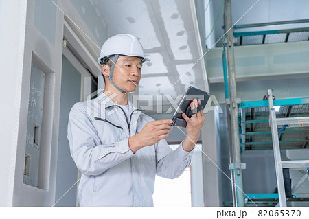 建築現場でタブレットを見ながら現場確認をする現場監督 82065370